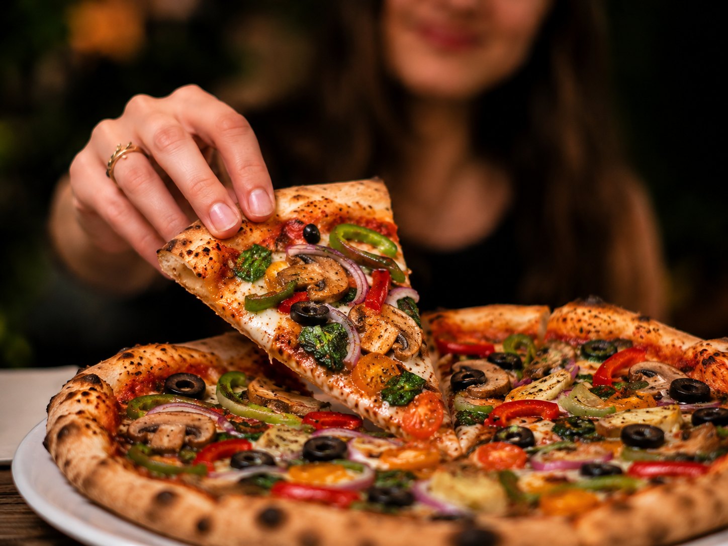 Pulling a fresh slice from a loaded FORNO pizza